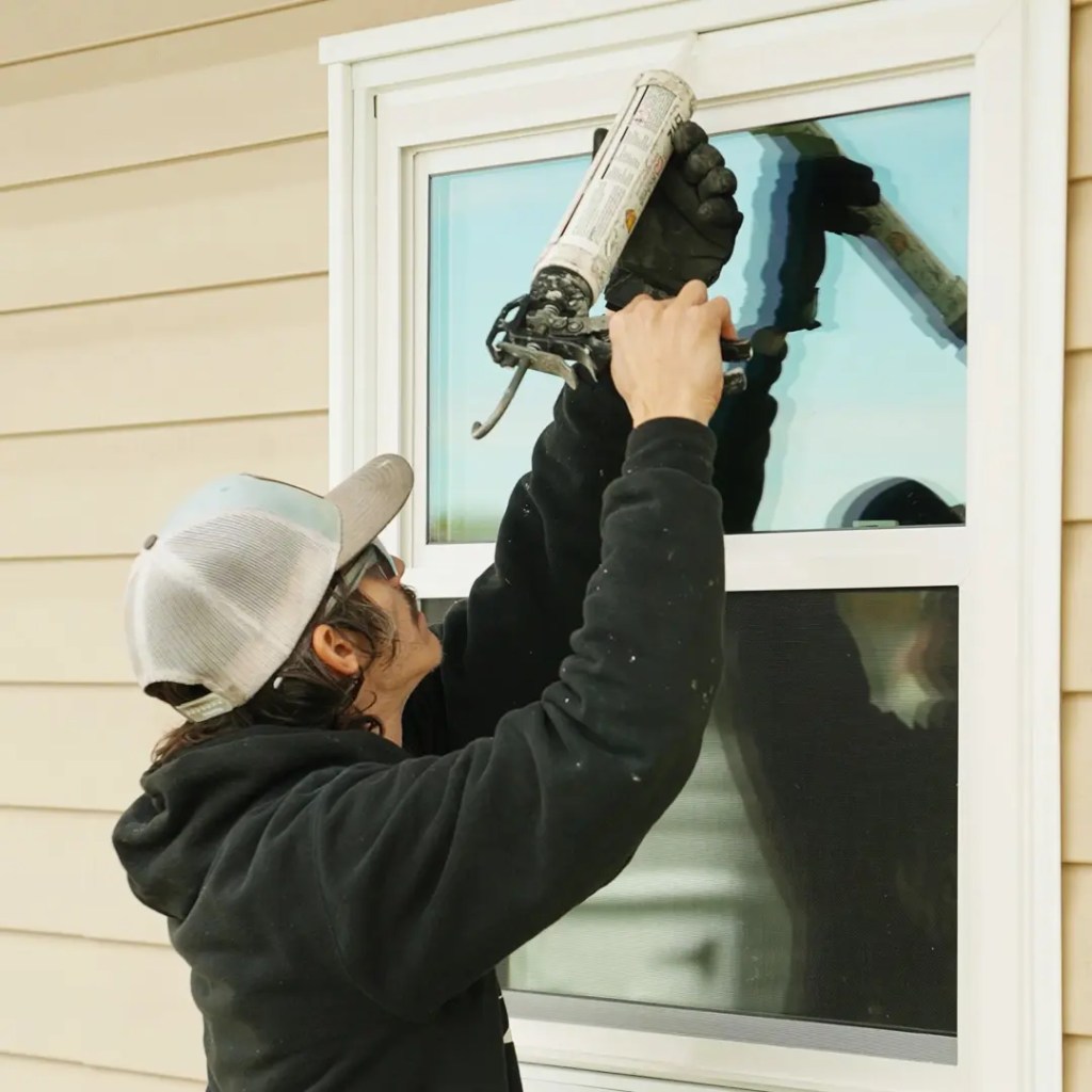 Front page A window installer applying seal on the newly installed window